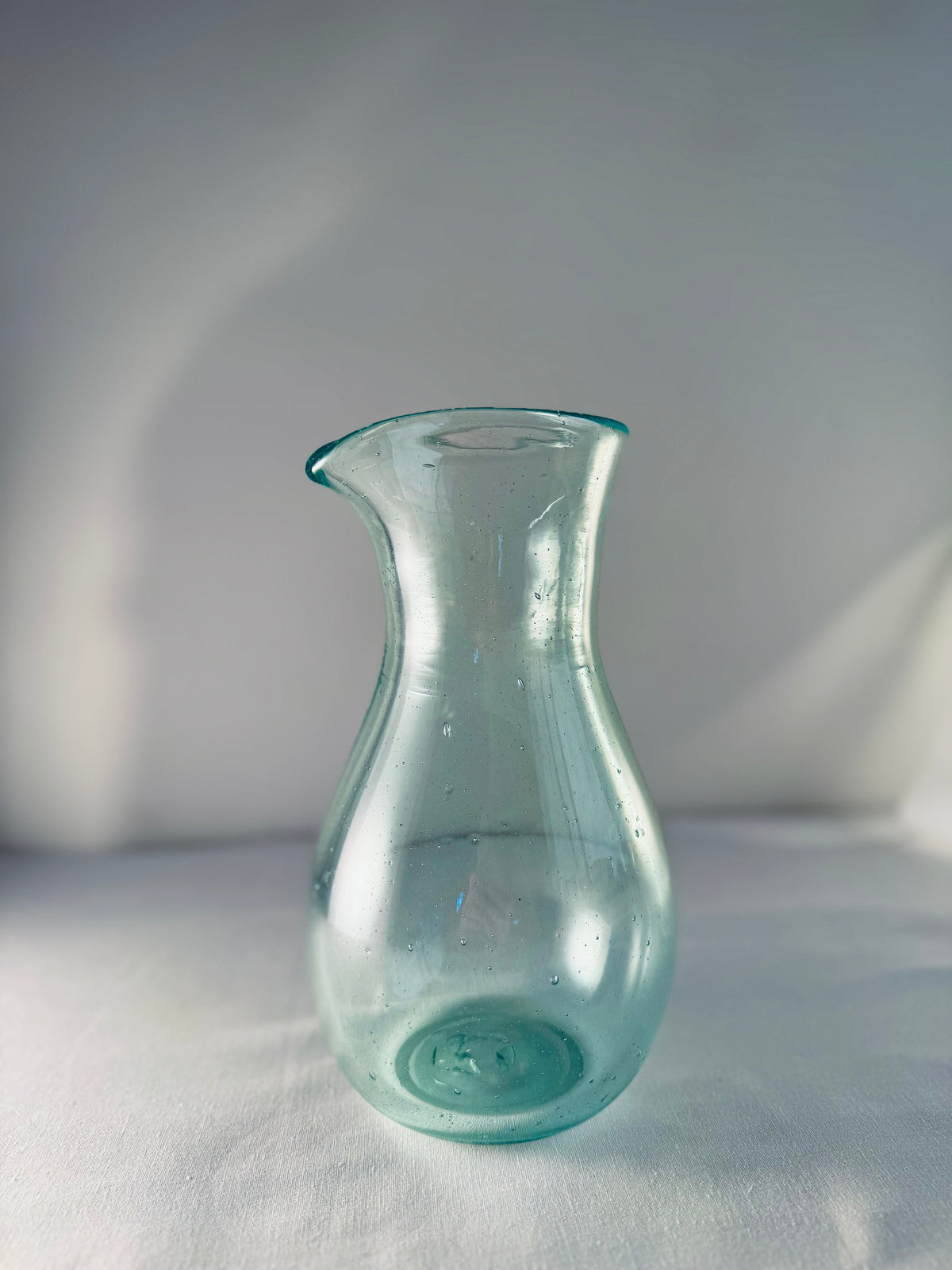 Enyo Living Germany Ocean Green glass carafe with a pouring spout and bulbous base.