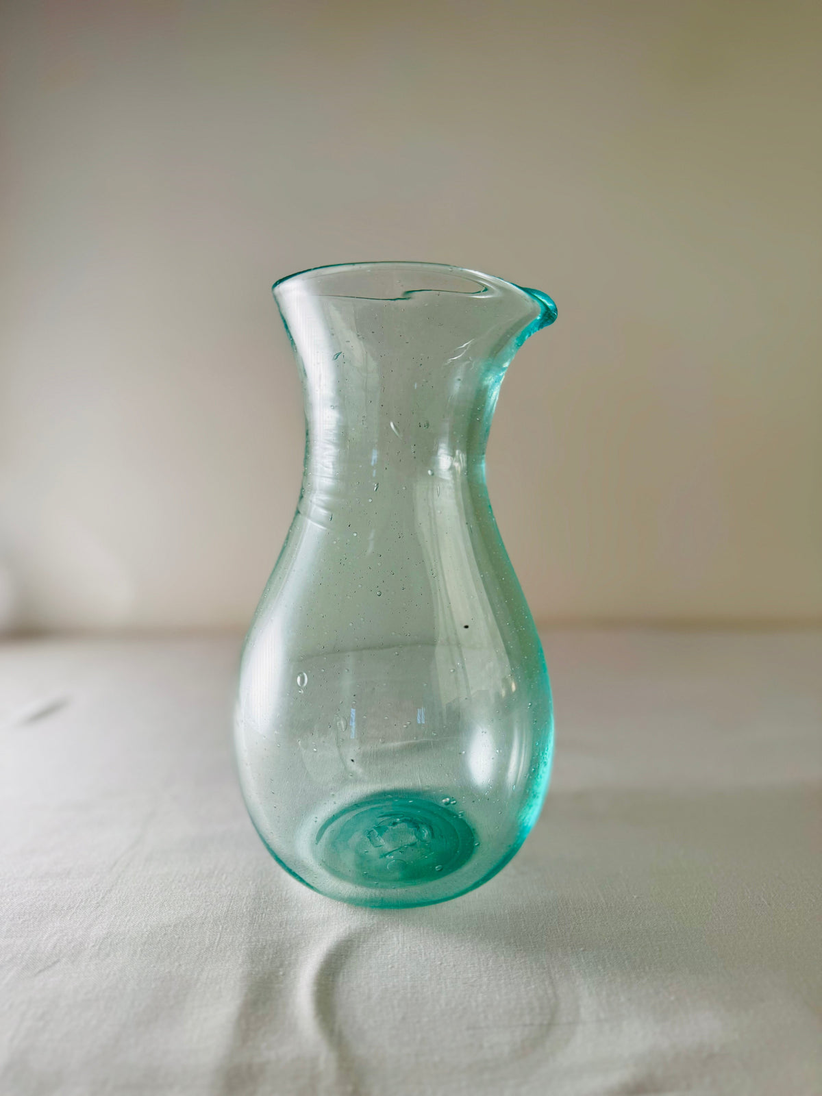 Enyo Living Ocean Green glass carafe with a pouring spout and curved handle. Clear sea-green glass.
