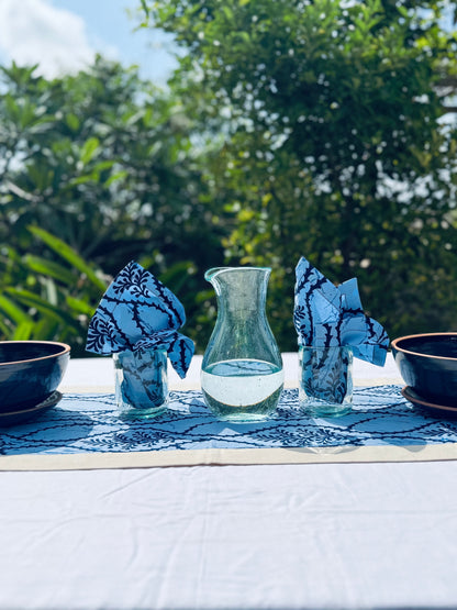 Enyo Living Karaffe Ocean Green glass carafe with water on a table with blue patterned napkins and bowls.